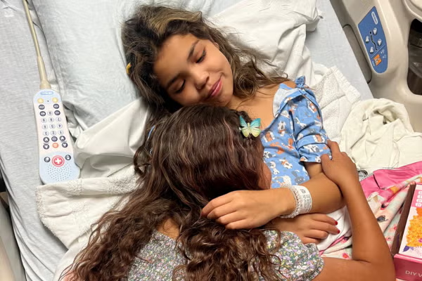 Reggie in hospital hugging sister
